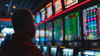 A man is interacting with an electronic device known as a slot machine at a casino. The colorful display device and glass of drink add to the dark, recreational atmosphere of the event