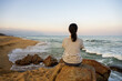 A woman sitting at beach and looking to sunrise.