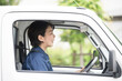 © kapinon - 新緑の中トラックを運転する中年の作業着の女性の横顔　運送や配送業などのイメージ