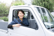 © kapinon - トラックを運転する中年の作業着のガテン系の女性　カメラ目線　運送や配送業などのイメージ