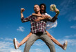 © Volodymyr - Crazy couple having fun outdoor. Young fun excited couple piggyback ride in summer day. Happy young couple having fun on summer sunny day near sky background. Couple piggyback ride.
