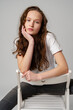 Curly girl model posing on a chair against gray background