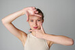 Woman Posing for Picture With Hands on Head on gray background