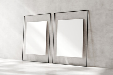 Two empty picture frames leaning against a textured wall, casting soft shadows on a sunny day, offering a template for art display