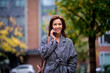 Attractive mid adult woman walking on the city street and using her smartphone