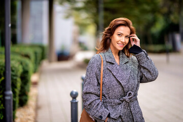 Wall Mural - Brunette haired woman wearing tweed coat and walking outdoors in the city street on autumn day