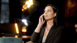 Close-up focus of a serious businesswoman talking on a mobile phone in a restaurant. Close-up of a beautiful woman talking on the phone while having dinner in a restaurant.
