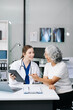 © Nuttapong punna - Portrait of female doctor explaining diagnosis to her patient. Doctor Meeting With Patient In Exam Room. A medical practitioner reassuring a patient .