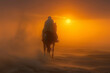 Silhouette of a lone rider on horseback at sunset in a dusty desert