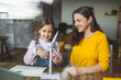 © Westend61 - Happy grandmother with granddaughter sitting with wind turbine model at home