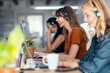 © Westend61 - Happy businesswoman talking through headset sitting amidst colleagues at desk in office