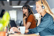 © Westend61 - Businesswoman talking through headset sitting amidst colleagues at desk in office