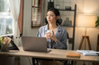 © Thitisak - Asian business woman working on computer looking at documents at office