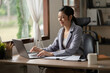 © Thitisak - Asian business woman working on computer looking at documents at office