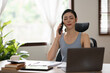 © Thitisak - Asian woman talking on the phone, working with customers, office