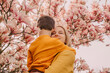 © Westend61 - Smiling mother carrying son by blossoming magnolia tree in garden