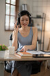 © Thitisak - Asian woman talking on the phone, working with customers, office