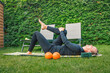 Gymnastics in the garden. A woman is laying on a mat with two orange balls next to her