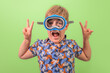 A boy in a blue underwater mask and shirt. The boy rejoices at the onset of holidays and vacation. On a green background