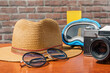 Tourist still life. A hat, sunglasses, and a camera are on a table