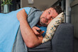 Emotional portrait of a man watching TV while lying on the sofa. The man was surprised by what he saw. A man is laying on a couch with a remote in his hand