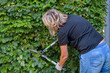A woman is cutting some plants with a pair of scissors in summer