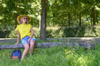 Loneliness on a walk. A woman in a yellow shirt and blue shorts sits on a log in a grassy area