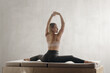 Beautiful young woman doing full split on the background of gray wall, Serene and flexible: Healthy woman's yoga split