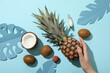 Set of tropical fruit, hand and paper tropical leaves on blue background, top view