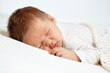 Sleeping Baby. Close up Newborn Face Portrait with long Hair. One month Boy sleep on Stomach under White Blanket. Infant Health Care and Development