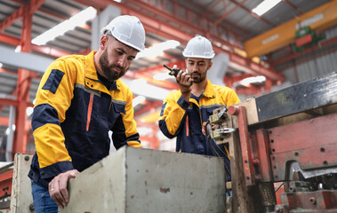 Wall Mural - Skilled manager on job training latin technician working in metal sheet production factory. Industrial engineer and team standing at manufacturing facility talking mechanic machinery maintenance job.