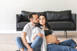 Pregnant couple sitting on living room floor