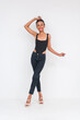 Confident mixed race woman in black bodysuit and jeans posing on white background