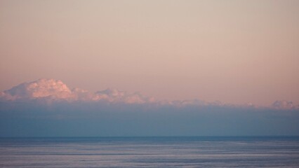 Wall Mural - Fluffy clouds sunset sky above calm sea with space for text. Miminal coastal banner.