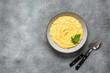 Mashed potatoes in a bowl with cutlery on a gray rustic background. Top view, copy space.