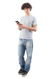 Fototapeta Panele - Young man, smiling and handsome, using his smartphone with earphones to listen to music or voice message. He looking into the camera with his blue eyes, isolated on white background in full-body shot