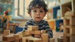 Young child with curly hair wearing striped sweater sitting on floor playing with wooden blocks in colorful room with toys and books.