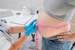 Doctor measuring the volume of a pregnant woman's abdomen using a tape in inches. 