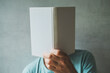 Male reader hiding his face behind the white mockup book