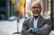 © Danko - Portrait Confident black business man in a stylish suit standing on office block looking at the camera with a serious expression