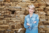Fototapeta Panele - Thoughtful Woman in Denim Shirt Leaning Against Stone Wall