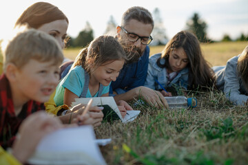 Wall Mural - Young students learning about nature, forest ecosystem during biology field teaching class, writing notes. Teachers talking with children during outdoor active education.