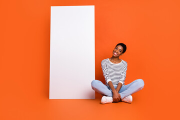 Wall Mural - Photo of sweet dreamy butch lady dressed sweater sitting legs crossed gadget empty space isolated orange color background