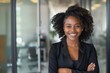 © Danko - Happy african american young woman standing with arms crossed in office