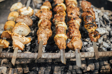 Delicious kebab roasting in fire pit close up. Meat and vegetable bbq grilling in smoke in modern fireplace pit. Summer picnic outdoor. 4 of july