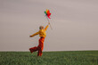© VISTA by Westend61 - Woman holding multi colored pinwheel toy and standing in green wheat field on sunny day