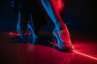 Legs of gorgeous woman in high heels shoes under red illumination, laser light, neon club. Projection illusion mapping