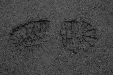 The footprints of a boot are traces of a person on moist soil that begins to dry out from the sun, shoe prints on soft ground, photo during the day