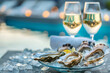 Romantic setting with plate of fresh oysters and two glasses of sparkling wine on terrace against sea