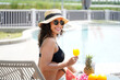 Summer time and Vacations. Women lifestyle relaxing and drinking juice orange so happy in luxury swimming pool sunbath, summer day at the beach resort in the hotel. Summer Concept